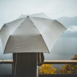 women holding a large umbrella in the drizzle, looking at mountains and a lake. How to support someone who is struggling.