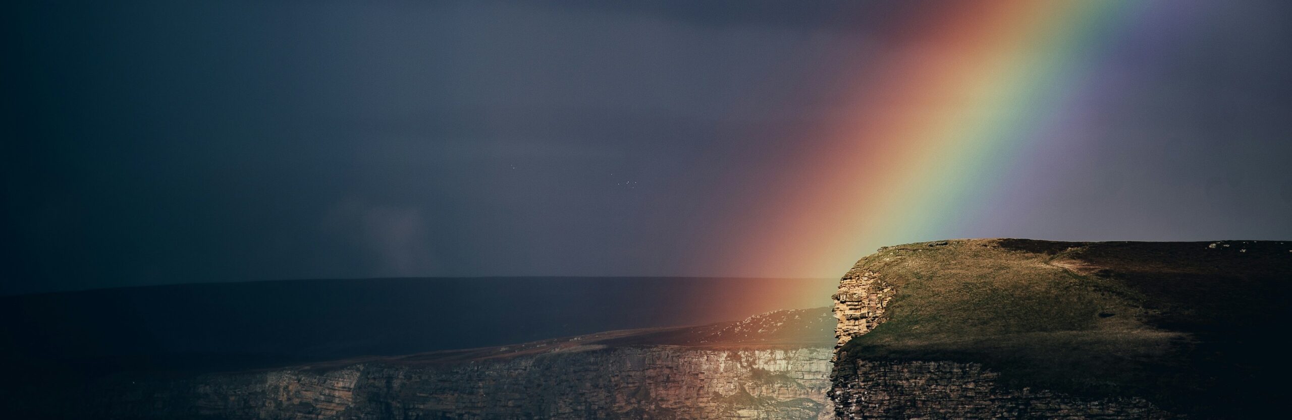 lgbtq therapy - image of a rainbow over cliffs